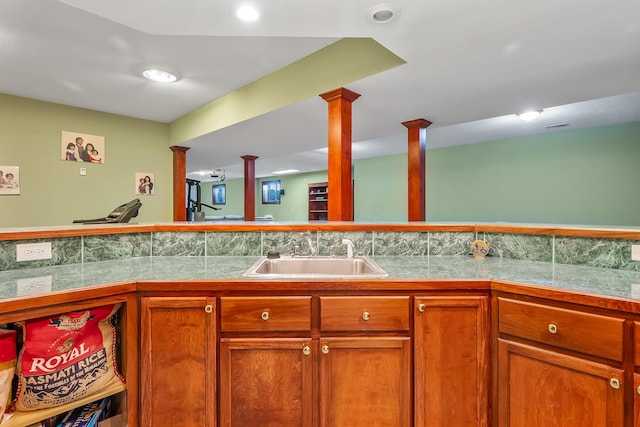 kitchen with decorative backsplash, ornate columns, and sink