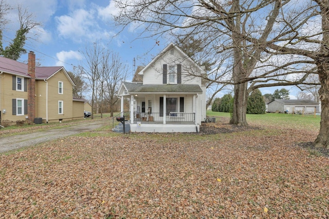 view of front of property featuring cooling unit, covered porch, and a front lawn