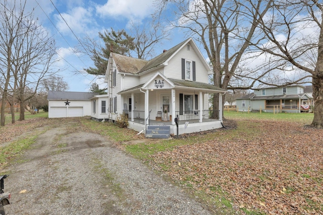 farmhouse-style home featuring a porch, a garage, and an outbuilding