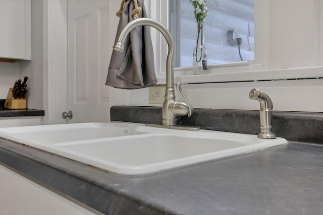 interior details featuring white cabinetry and sink