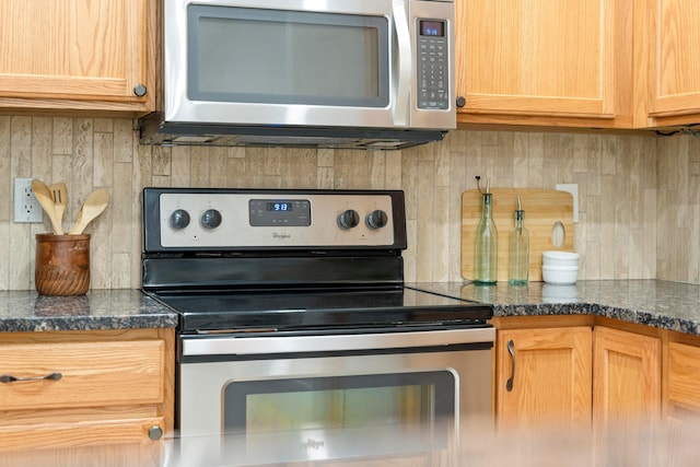 kitchen featuring appliances with stainless steel finishes, tasteful backsplash, and dark stone counters