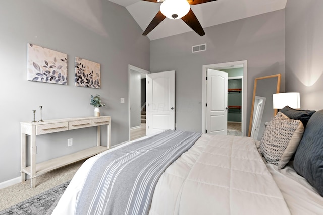 carpeted bedroom with ceiling fan, a closet, a walk in closet, and vaulted ceiling