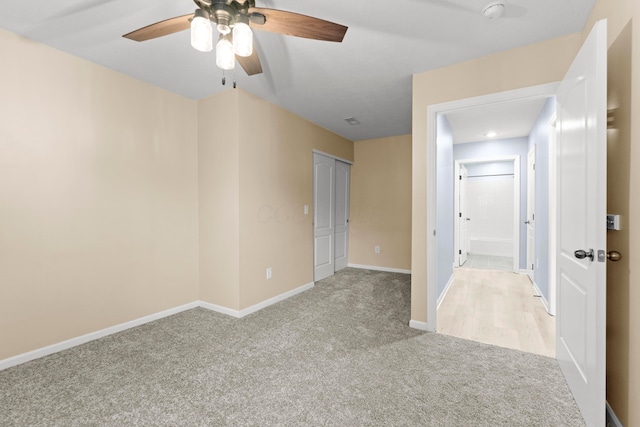 empty room with ceiling fan and light colored carpet