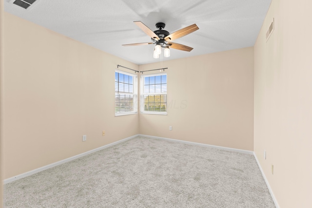 spare room featuring ceiling fan, light colored carpet, and a textured ceiling