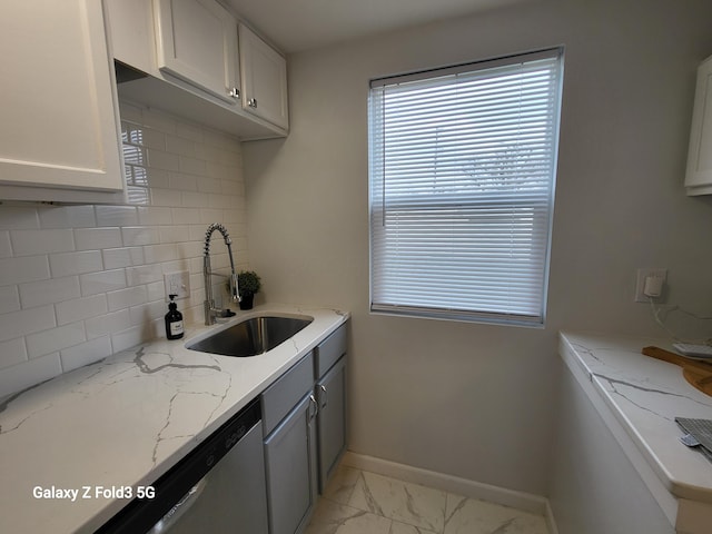 kitchen featuring decorative backsplash, light stone counters, sink, dishwasher, and white cabinets