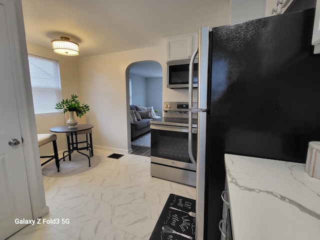 kitchen with light stone counters, white cabinets, and stainless steel appliances