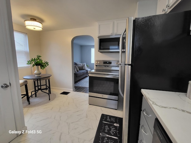 kitchen featuring light stone counters, white cabinetry, appliances with stainless steel finishes, and light hardwood / wood-style flooring