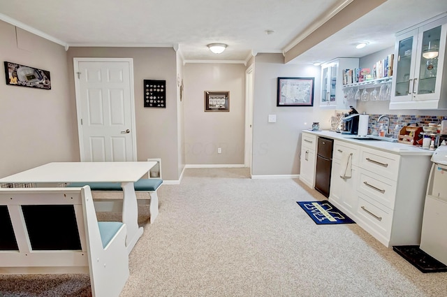 kitchen with crown molding, sink, light colored carpet, and white cabinets