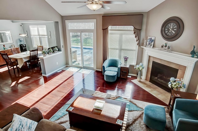 living room featuring a tiled fireplace, dark hardwood / wood-style flooring, lofted ceiling, and ceiling fan