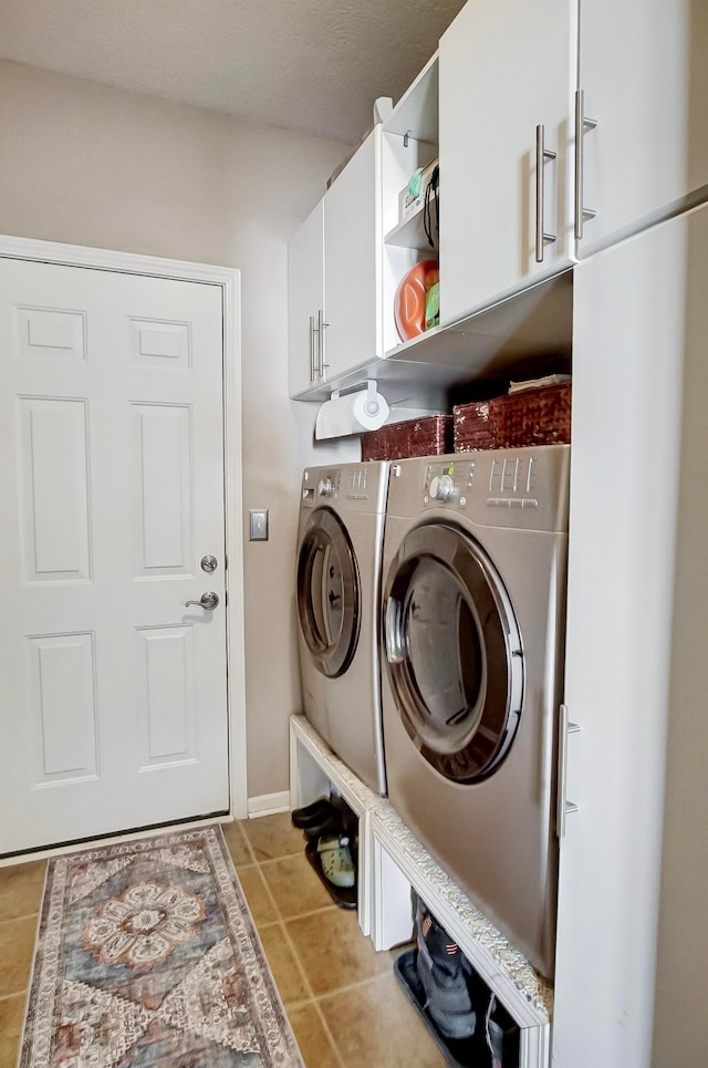 laundry area with cabinets, light tile patterned floors, and washing machine and clothes dryer