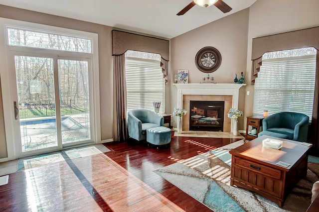 sitting room featuring a tiled fireplace, wood-type flooring, and ceiling fan