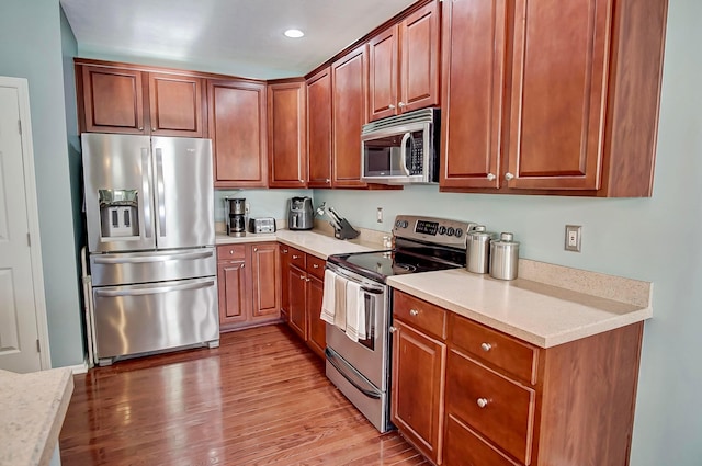 kitchen featuring light stone countertops, appliances with stainless steel finishes, and light hardwood / wood-style flooring