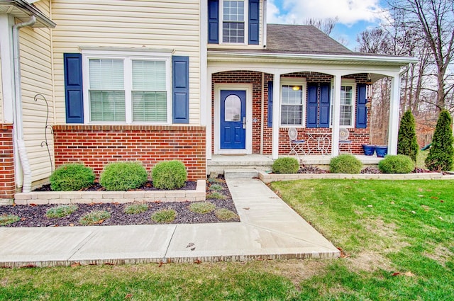 entrance to property with a lawn and a porch