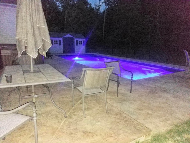 view of swimming pool featuring a storage shed and a patio area