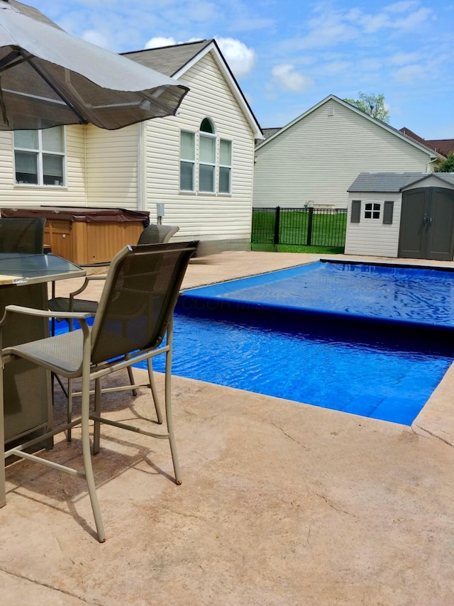 view of pool featuring a storage shed, a patio area, and a hot tub