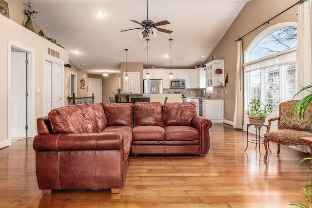 living room featuring light wood-type flooring, vaulted ceiling, and ceiling fan