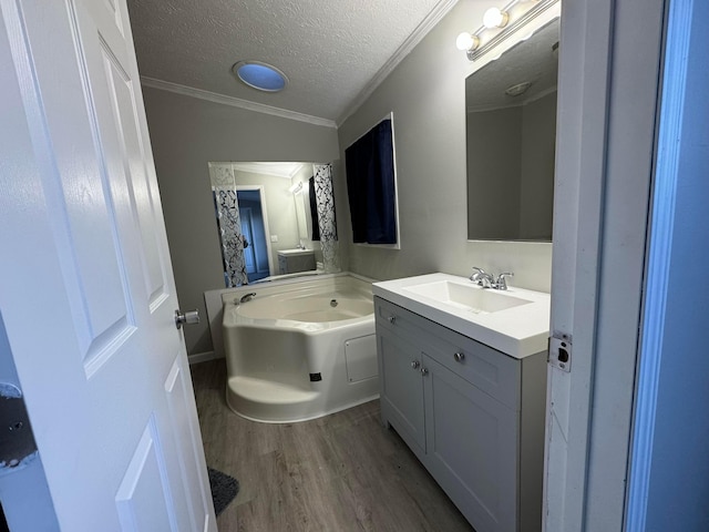 bathroom featuring a bath, wood-type flooring, a textured ceiling, vanity, and ornamental molding