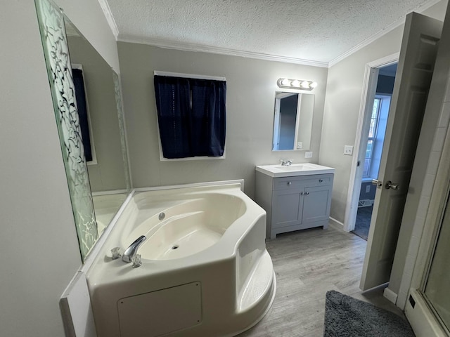 bathroom featuring a bathing tub, wood-type flooring, a textured ceiling, vanity, and ornamental molding