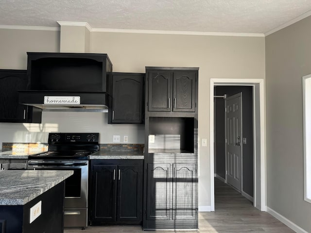 kitchen featuring hardwood / wood-style floors, dark stone counters, ventilation hood, crown molding, and stainless steel electric range oven