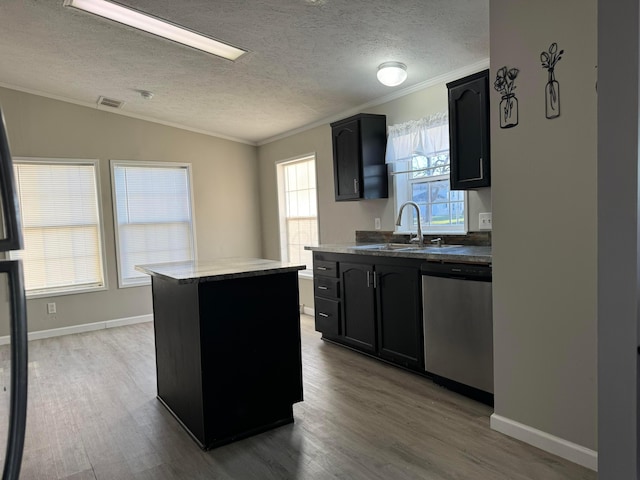 kitchen featuring dishwasher, wood-type flooring, a center island, and ornamental molding