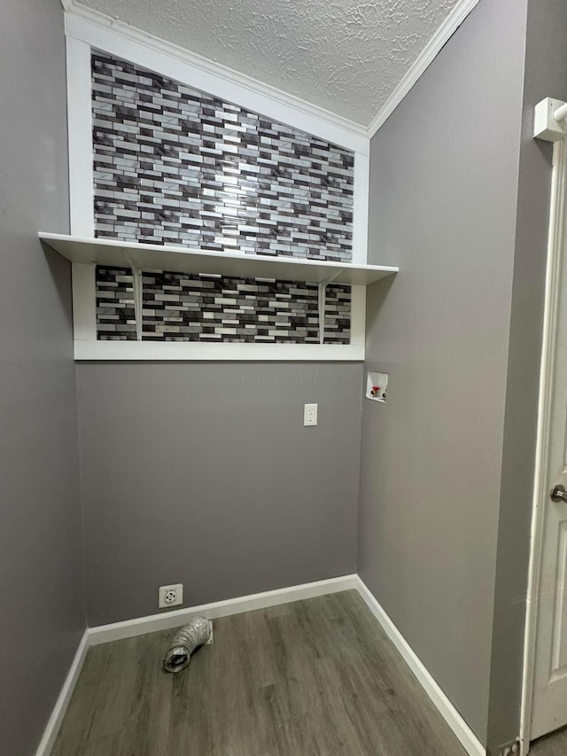 clothes washing area featuring crown molding and dark wood-type flooring