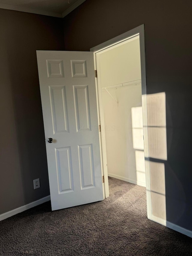 unfurnished bedroom with carpet flooring, ornamental molding, and a closet