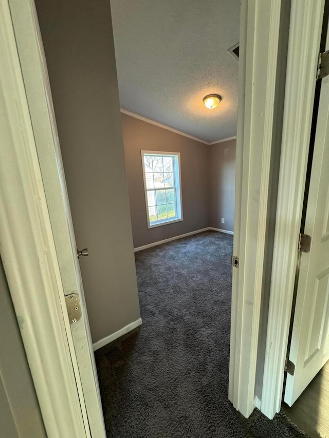 unfurnished room featuring a textured ceiling, vaulted ceiling, and dark colored carpet