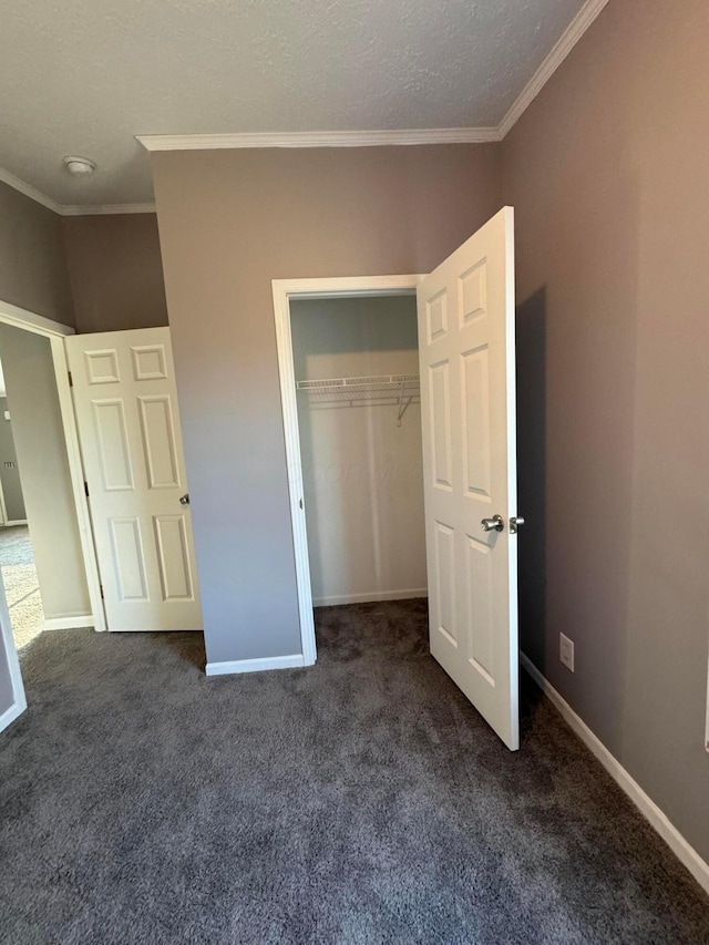 unfurnished bedroom featuring crown molding, a closet, dark carpet, and a textured ceiling