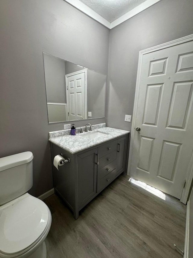 bathroom with vanity, a textured ceiling, hardwood / wood-style flooring, and toilet