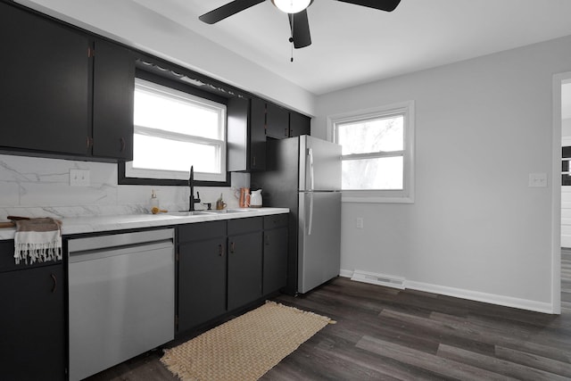 kitchen with backsplash, stainless steel appliances, ceiling fan, dark wood-type flooring, and sink