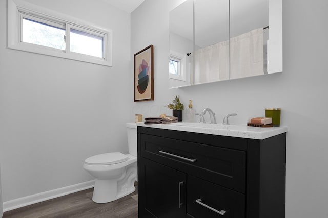 bathroom featuring a wealth of natural light, hardwood / wood-style floors, vanity, and toilet