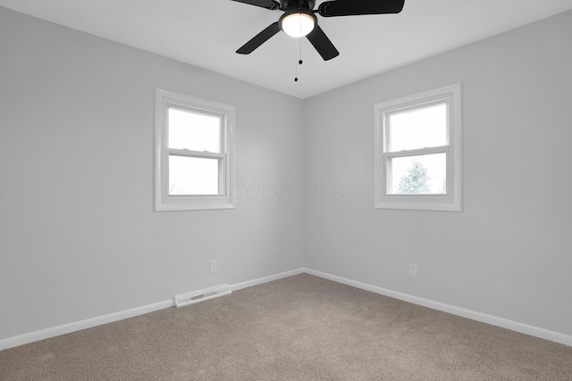 carpeted empty room featuring ceiling fan and a wealth of natural light