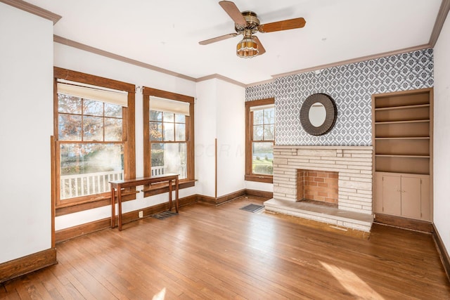 living room featuring wood-type flooring, a stone fireplace, ceiling fan, and a healthy amount of sunlight