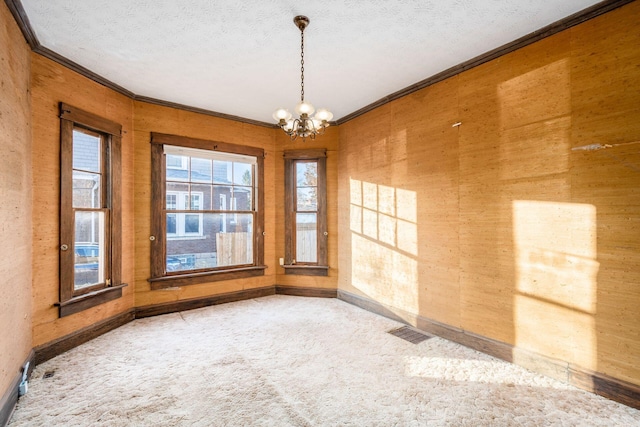 unfurnished room with carpet, ornamental molding, a textured ceiling, and a notable chandelier