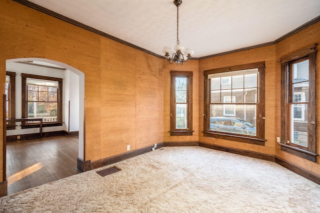 empty room with dark hardwood / wood-style flooring, ornamental molding, a textured ceiling, and an inviting chandelier