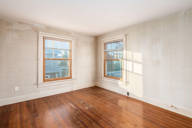 empty room with plenty of natural light and hardwood / wood-style flooring