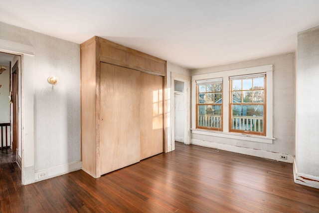 unfurnished bedroom with a closet and dark hardwood / wood-style floors