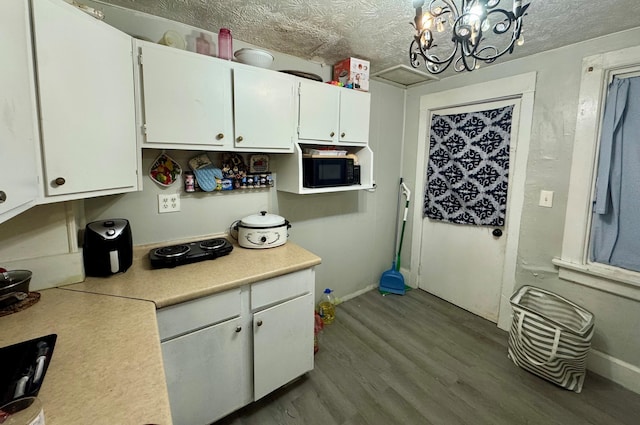 kitchen with white cabinetry, a chandelier, a textured ceiling, and hardwood / wood-style flooring