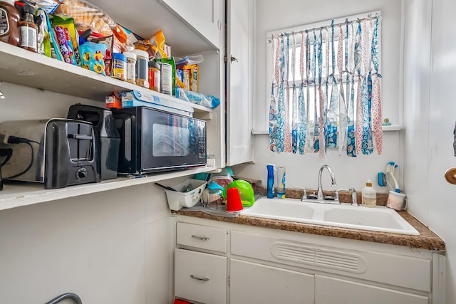 interior space featuring white cabinetry and sink