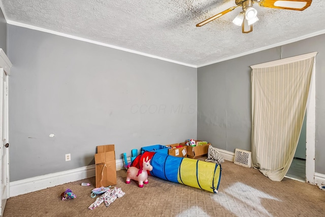 recreation room featuring a textured ceiling, ornamental molding, and ceiling fan