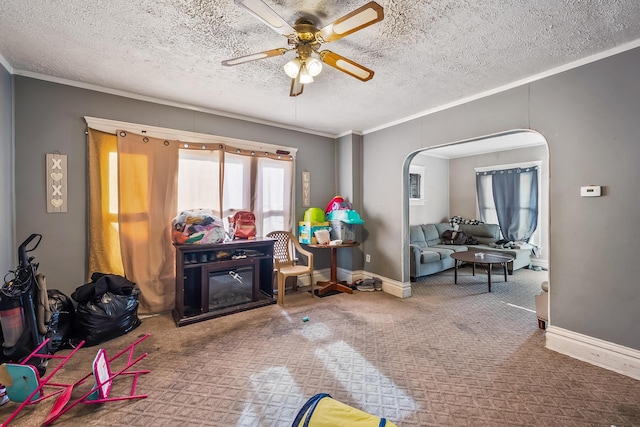 playroom with crown molding, a textured ceiling, ceiling fan, and carpet