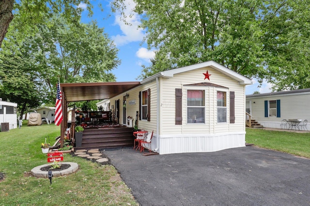 manufactured / mobile home featuring a carport and a front yard