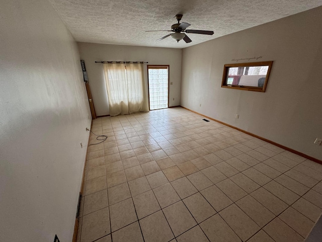 empty room featuring ceiling fan, light tile patterned floors, and a textured ceiling