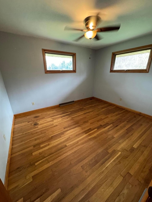 unfurnished room with ceiling fan, wood-type flooring, and a wealth of natural light