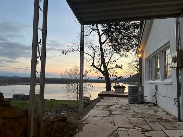 patio terrace at dusk featuring a water view and central AC