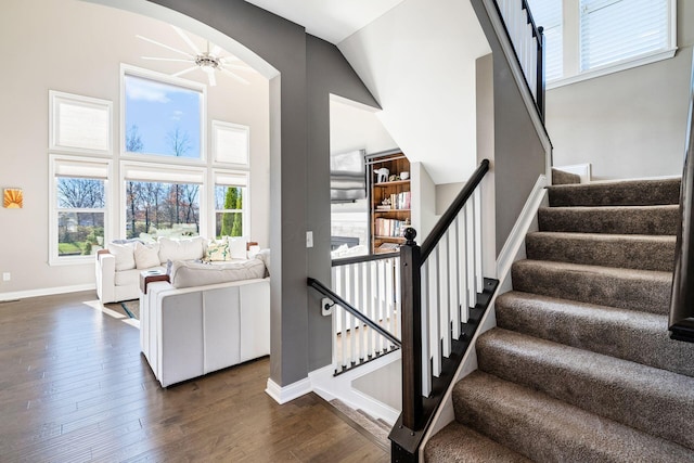 stairway with ceiling fan, plenty of natural light, vaulted ceiling, and hardwood / wood-style flooring