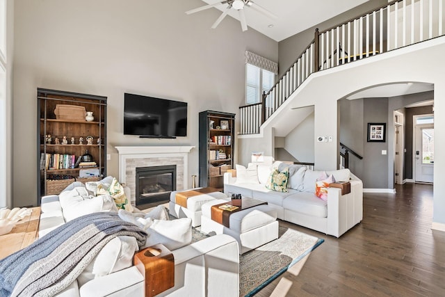 living room with a tiled fireplace, a wealth of natural light, dark hardwood / wood-style flooring, and a towering ceiling