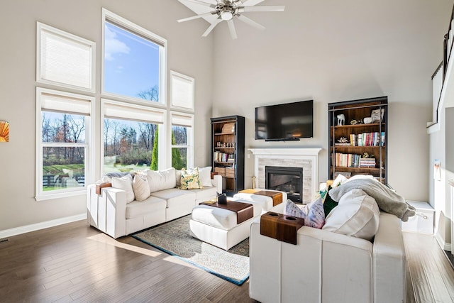 living room with ceiling fan, dark wood-type flooring, and a high ceiling