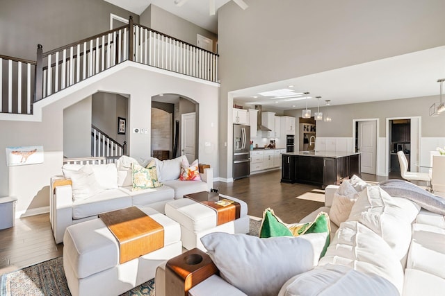 living room with sink, dark wood-type flooring, and a high ceiling