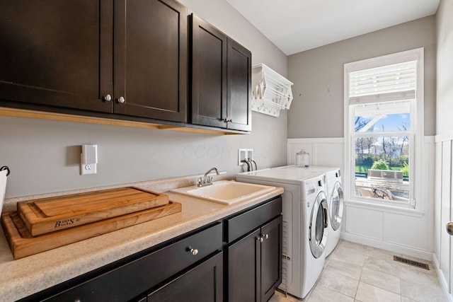 clothes washing area featuring light tile patterned flooring, cabinets, sink, and washing machine and clothes dryer